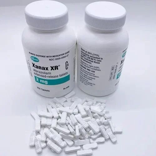 Xanax XR medication, each containing 2 mg of alprazolam. The bottles are white with green and blue labeling that specifies the product as "Xanax XR 2 mg extended-release tablets.